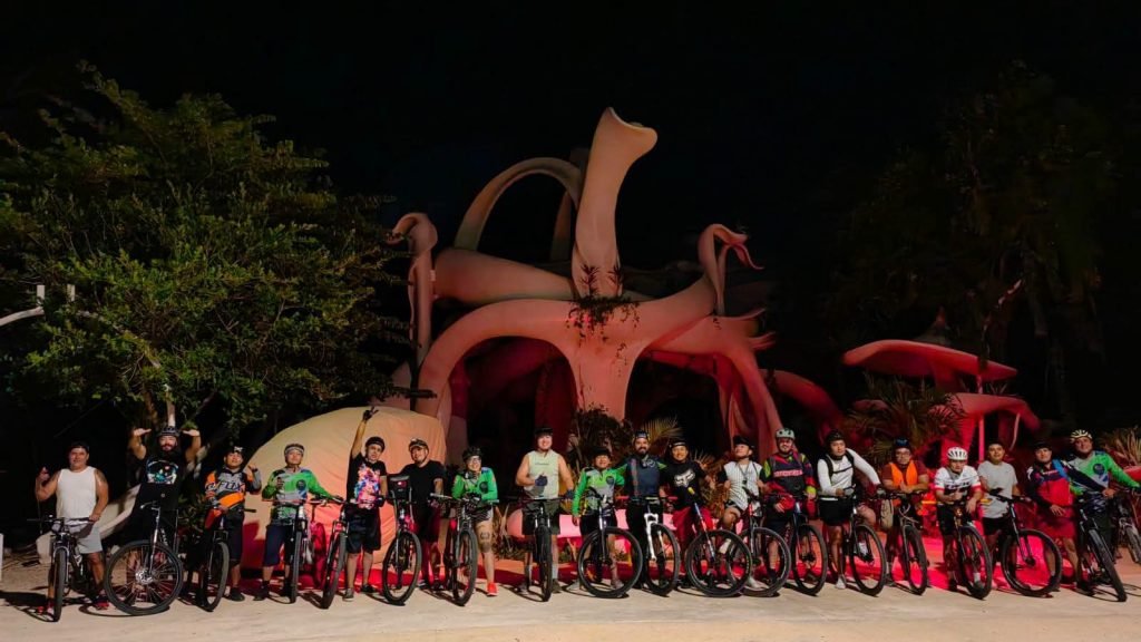 Group of cyclists riding through Tulum streets at night as part of RodandoXTulum weekly bike ride