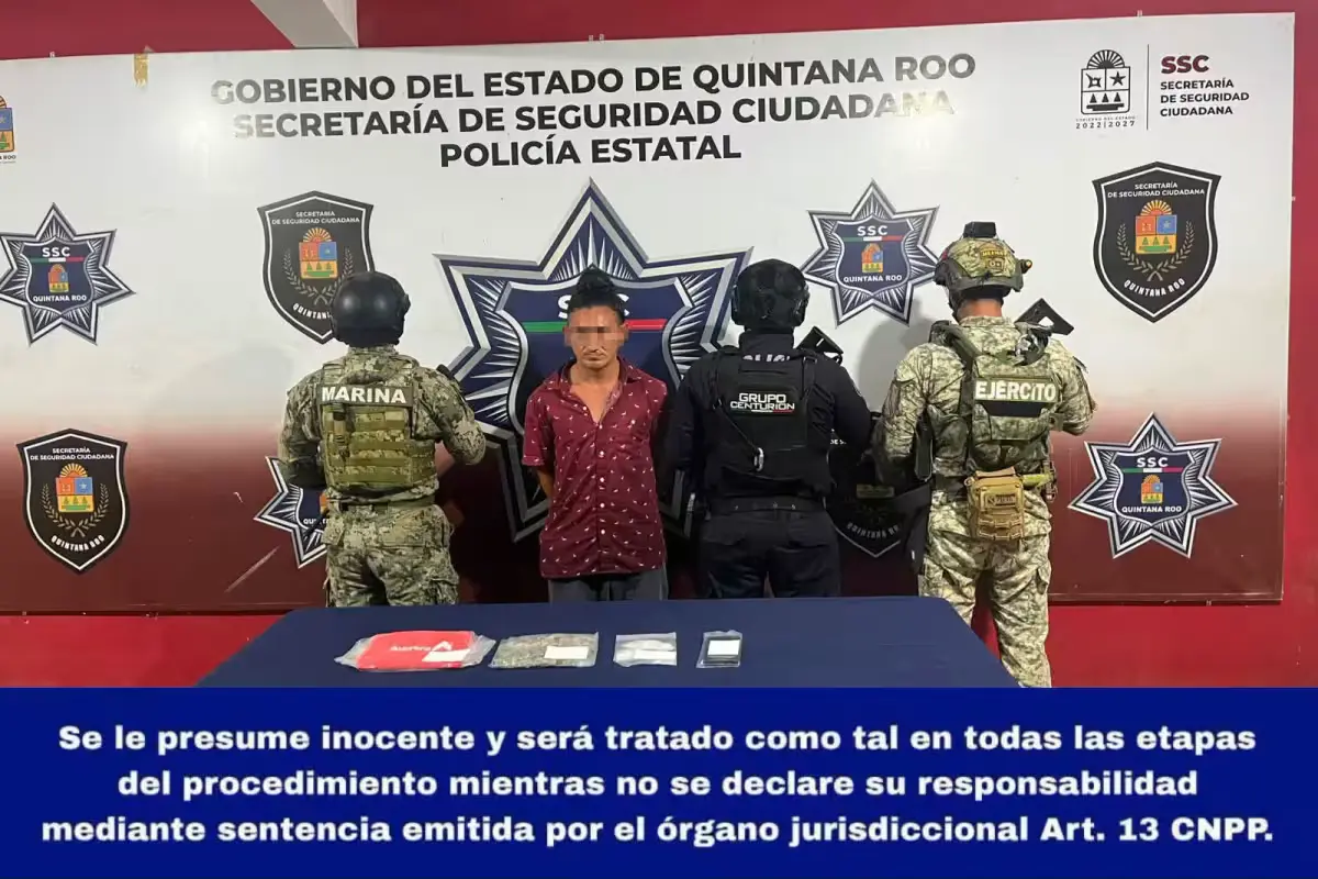 A man in handcuffs stands next to police officers after being arrested on Holbox Island