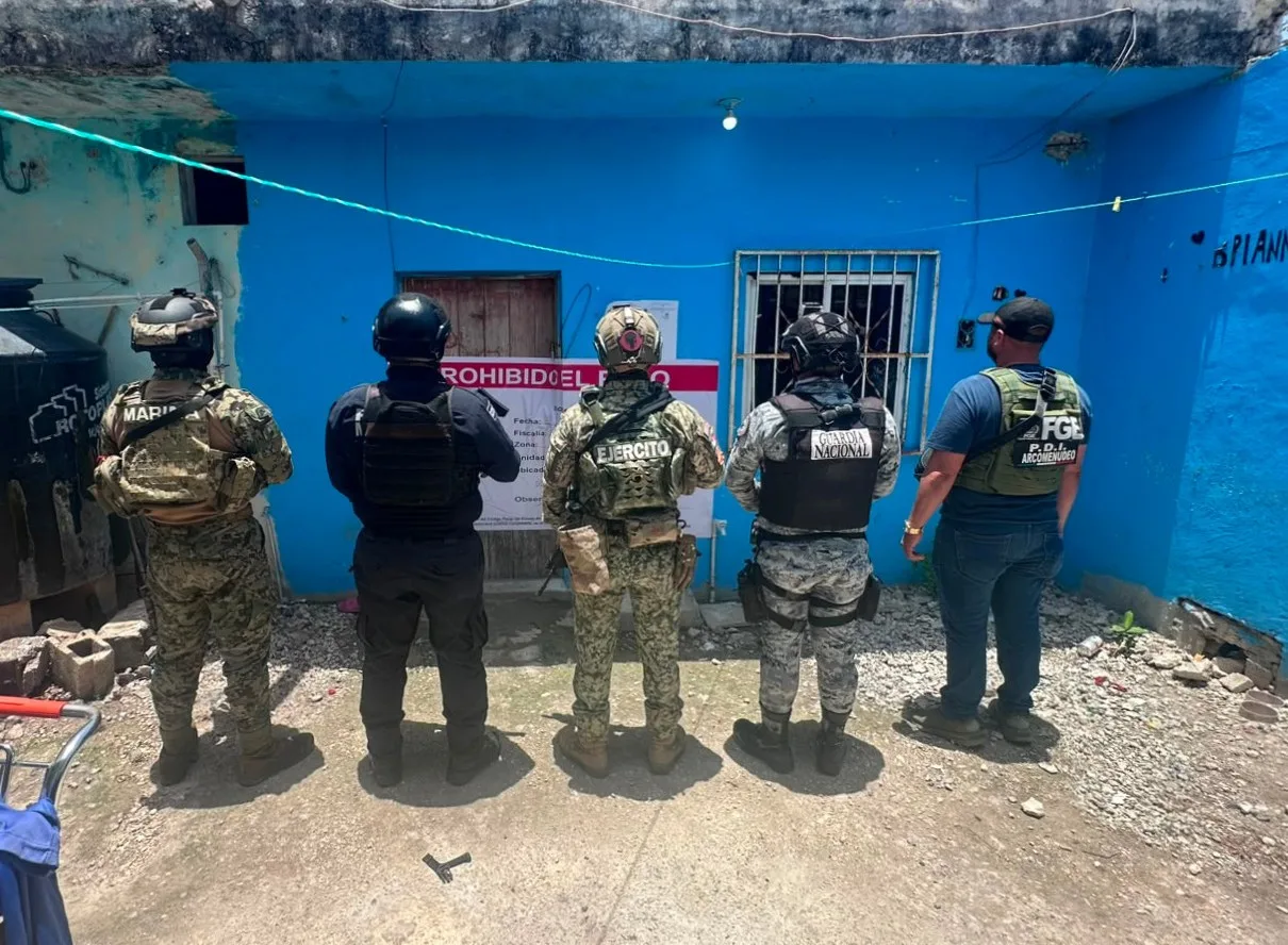 Police officers stand outside a building during a drug raid in Quintana Roo