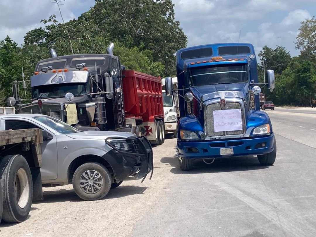Line of dump trucks parked on the shoulder of a highway near Cancun International Airport as drivers protest