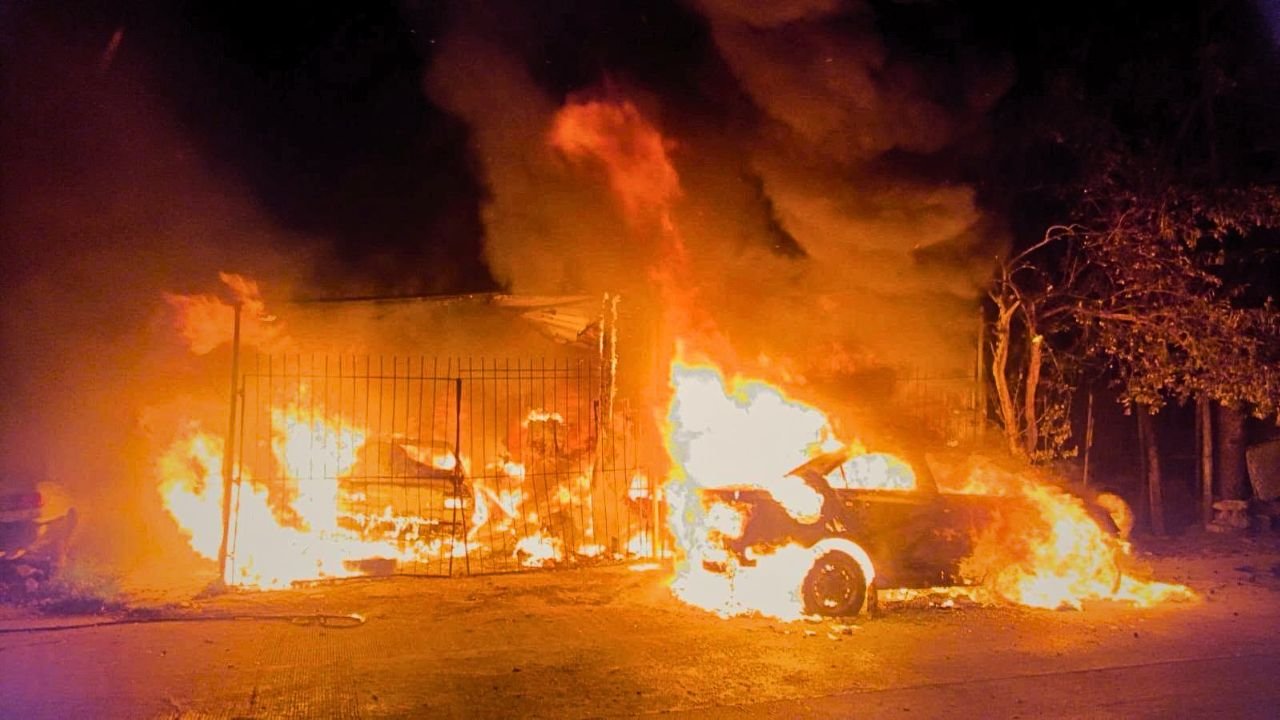 Firefighters spraying water on a burning auto shop in Cancun