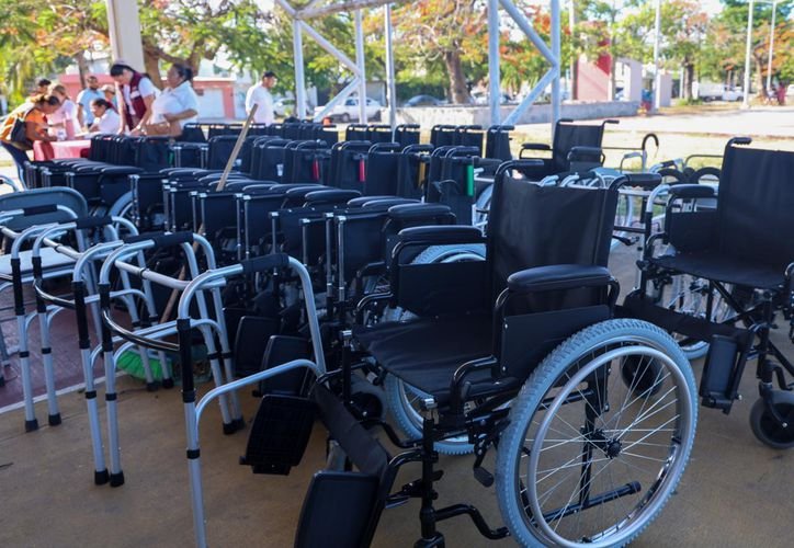 A person receiving a wheelchair from a DIF official in Quintana Roo