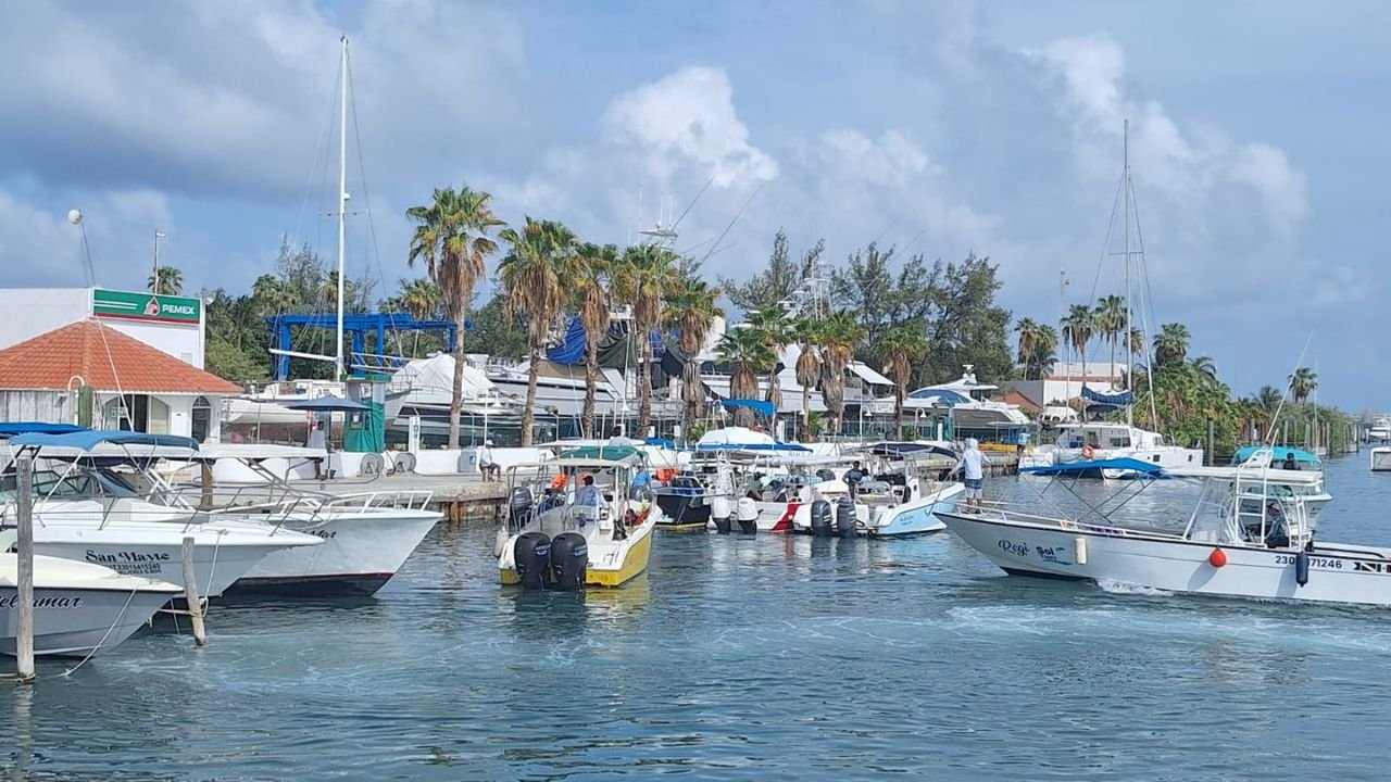 Boats docked at a marina in Cancun with a fuel price sign in the background