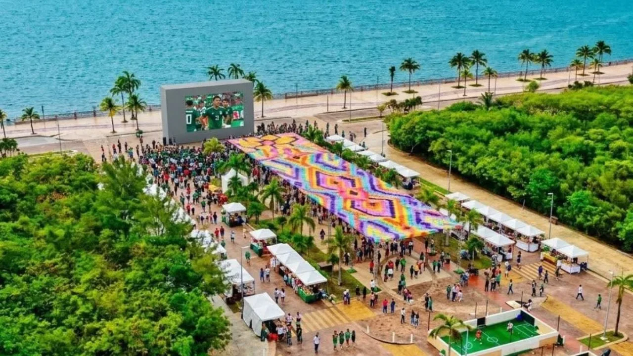 Large crowd watching a soccer match on a giant outdoor screen at a public event in Quintana Roo