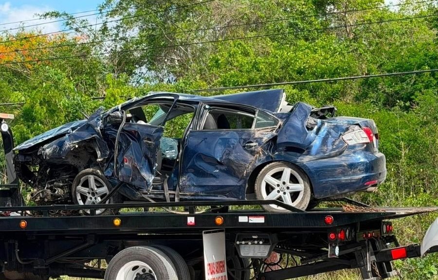 Two severely damaged vehicles on a highway after a head-on collision, with emergency personnel and National Guard present.