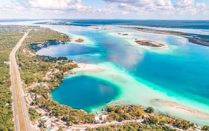 Aerial view of the Laguna de los Siete Colores in Bacalar, Quintana Roo, with turquoise waters and lush greenery.