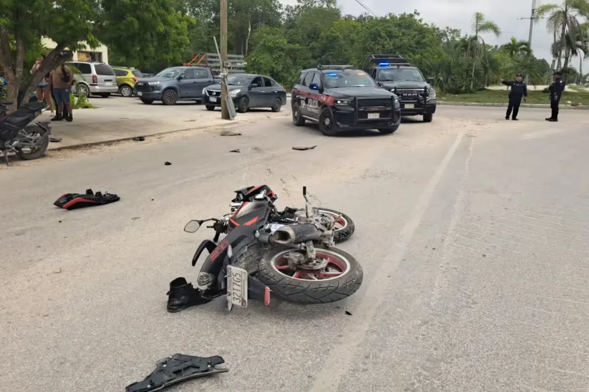 A motorcycle lying on the ground near a telephone pole after a crash in Tulum
