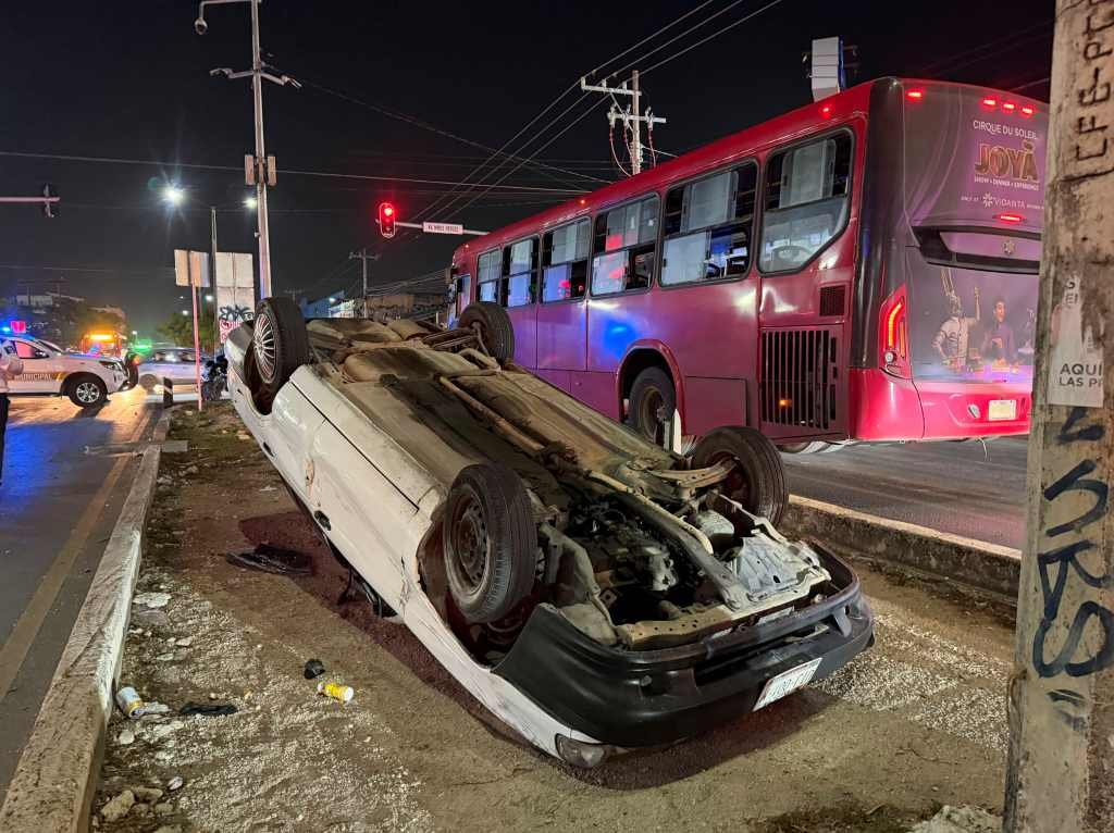 A silver car overturned on its side on a Cancun street after a crash involving a Mustang