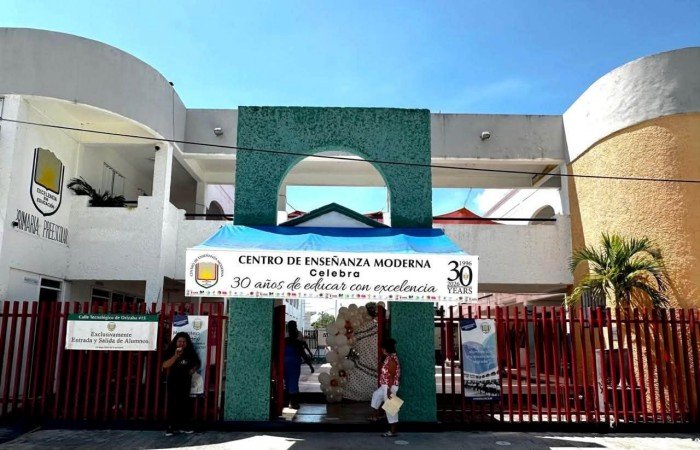 Parents holding signs protesting high taxes outside a private school in Chetumal, Quintana Roo