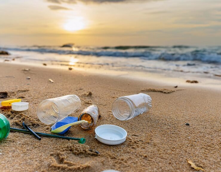 Plastic bottles and bags scattered on a sandy beach in Quintana Roo, Mexico