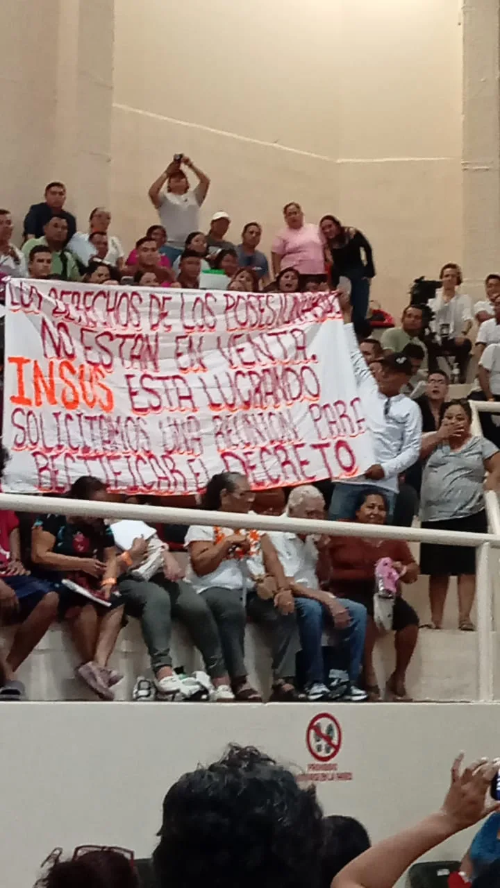 Residents hold a banner reading 'Los derechos de los posesionarios no están en venta' during a property title delivery event in Playa del Carmen.