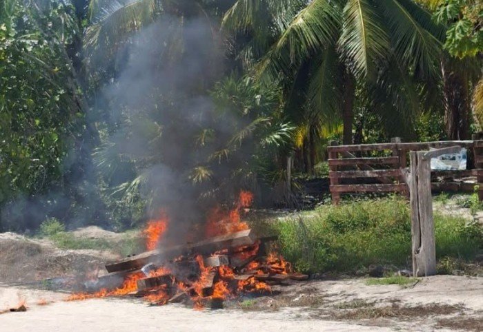 Residents of El Cuyo gather around a burning fence that had been blocking access to the beach
