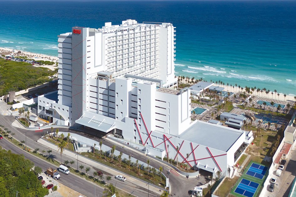 Exterior view of the Riu Ventura hotel in Cancun, a modern high-rise resort with pools and ocean views.