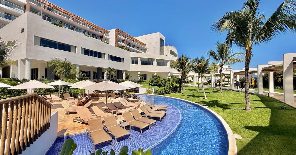 Exterior view of Royalton Splash Riviera Cancún hotel with pool and palm trees
