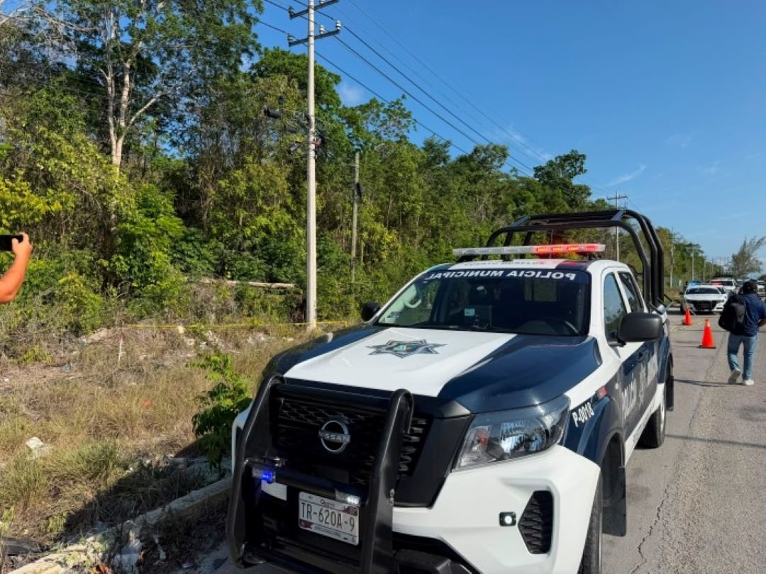 Police tape and vehicles at the site where two bodies were discovered on the Puerto Morelos-Cancun highway