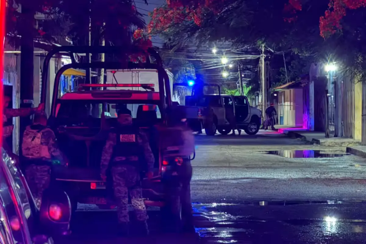 Police officers and military personnel stand guard outside a residential building during an operation in Cancun.