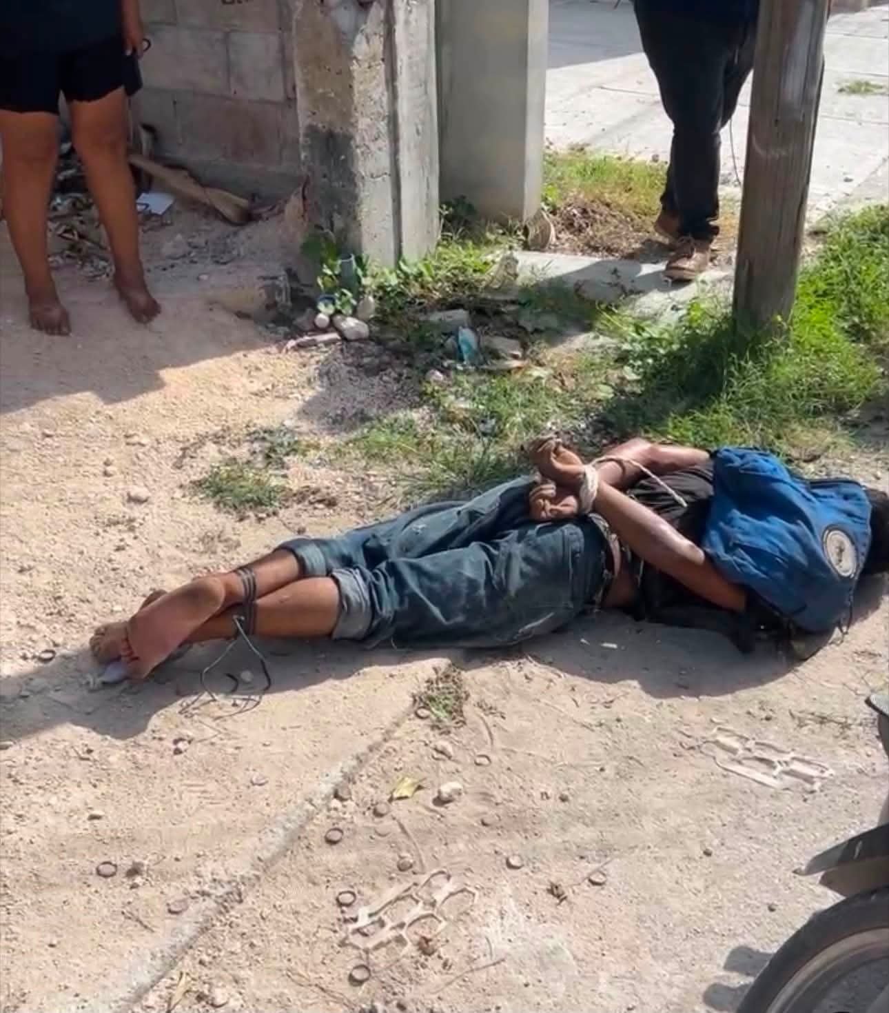 A man tied up on the ground surrounded by residents in Cancun