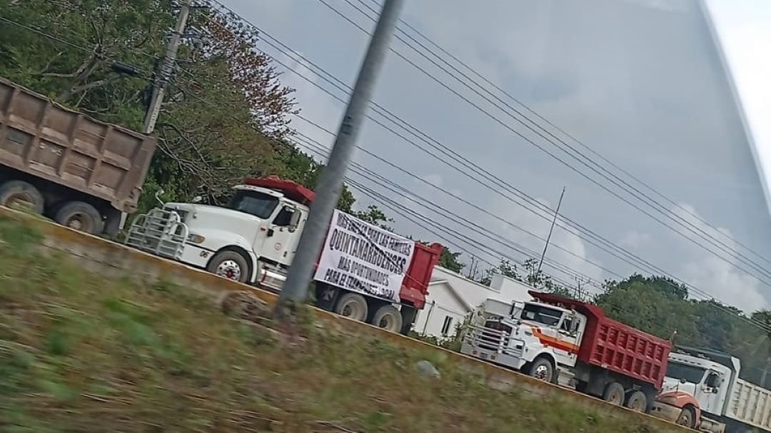 Dump trucks and trailers parked along the highway in Cancun as truckers prepare for a protest caravan