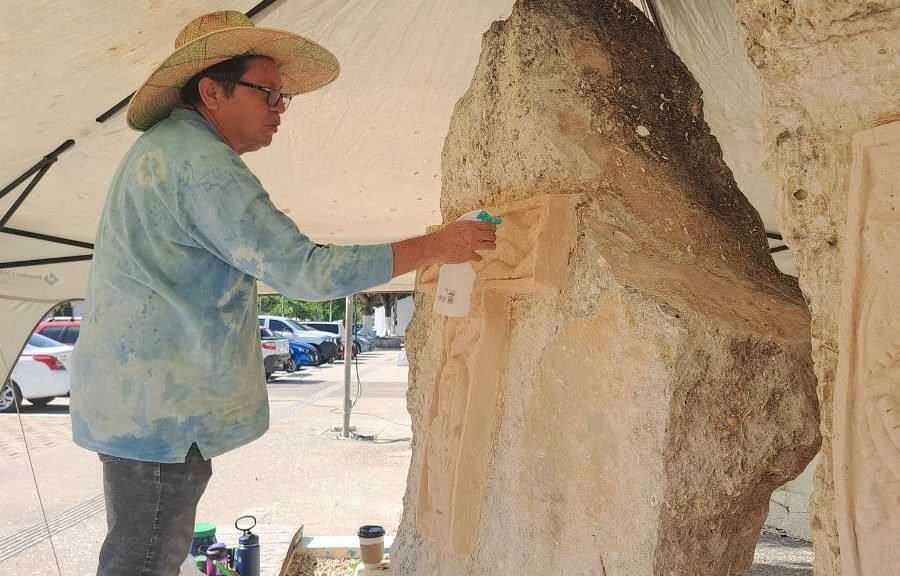 Artist applying natural pigments to the Tulum tourist letters in the park