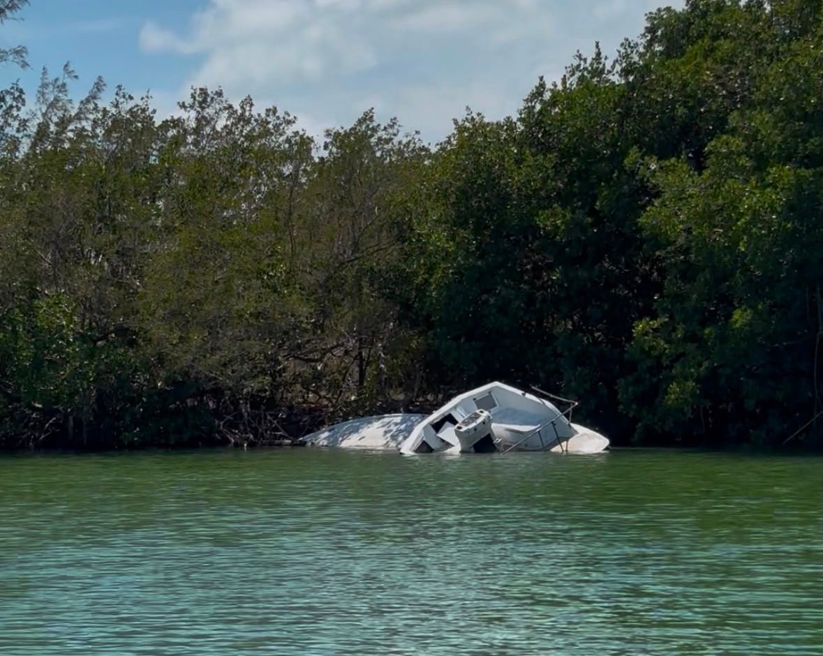 Workers remove an abandoned boat from the shore of Nichupté Lagoon during a cleanup operation in Cancún.