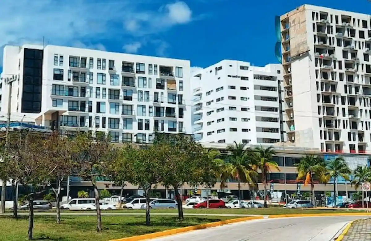 A residential development in Cancun, with construction cranes and new buildings under a bright sky