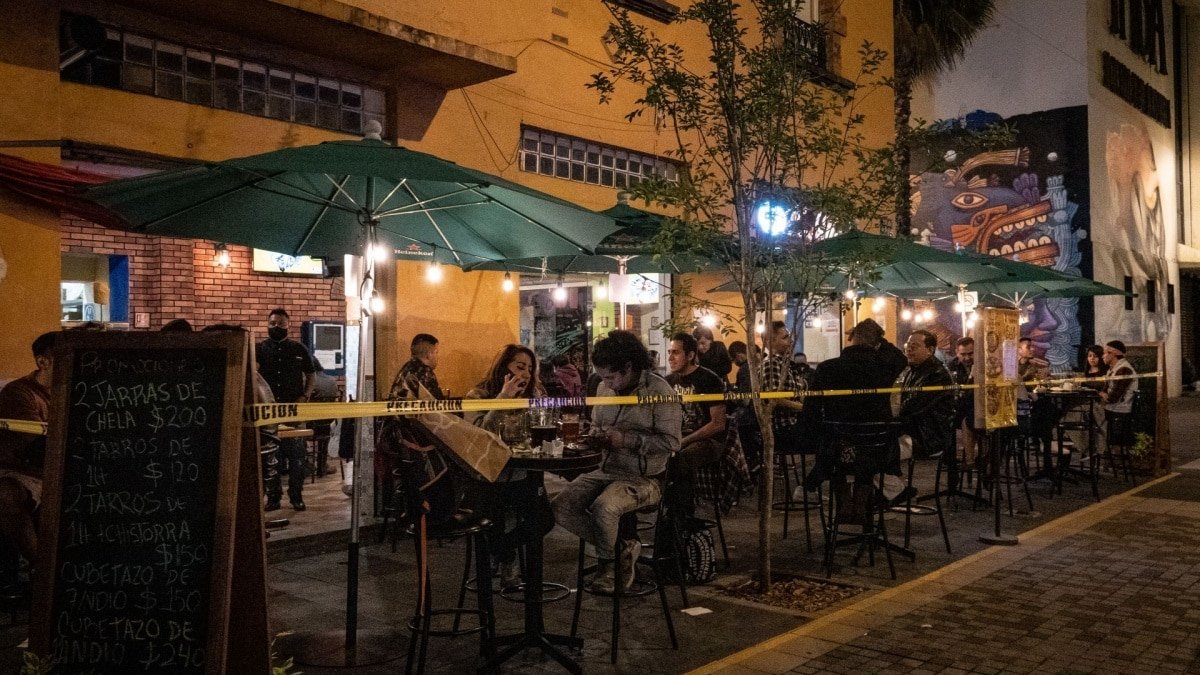 Customers socialize at a bar counter in Mexico, where bars contribute billions annually to the economy.