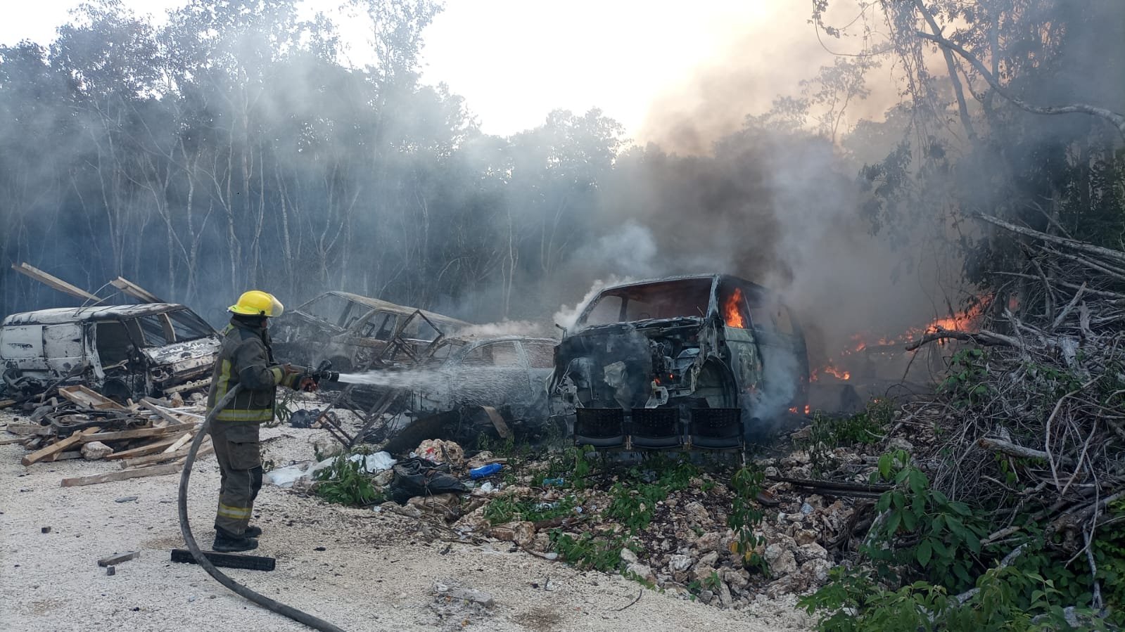 Firefighters spray water on burned vehicles at a scrapyard in the Continental Zone of Isla Mujeres.