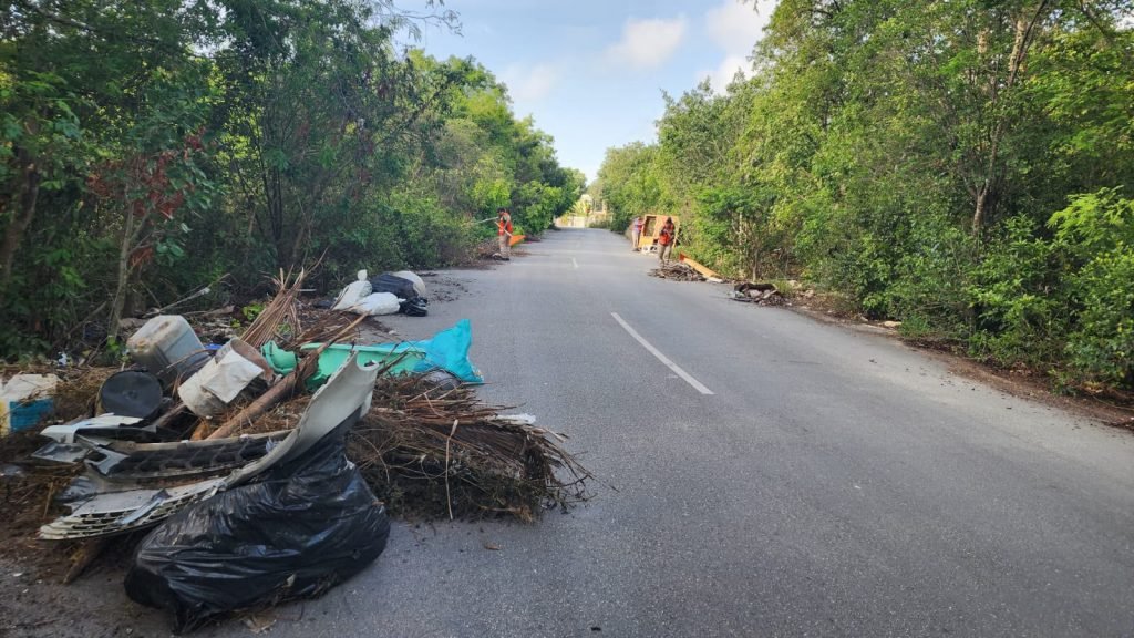 Illegal dump site in Tulum with trash bags, tires and debris scattered in a vacant lot