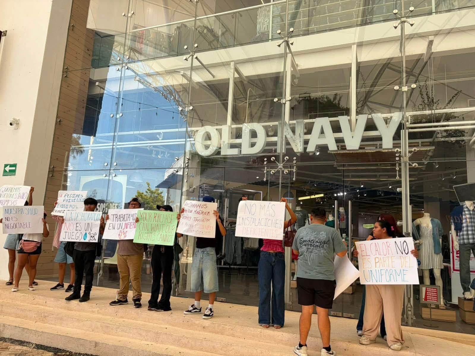 Workers hold protest signs outside the Old Navy store in Playa del Carmen