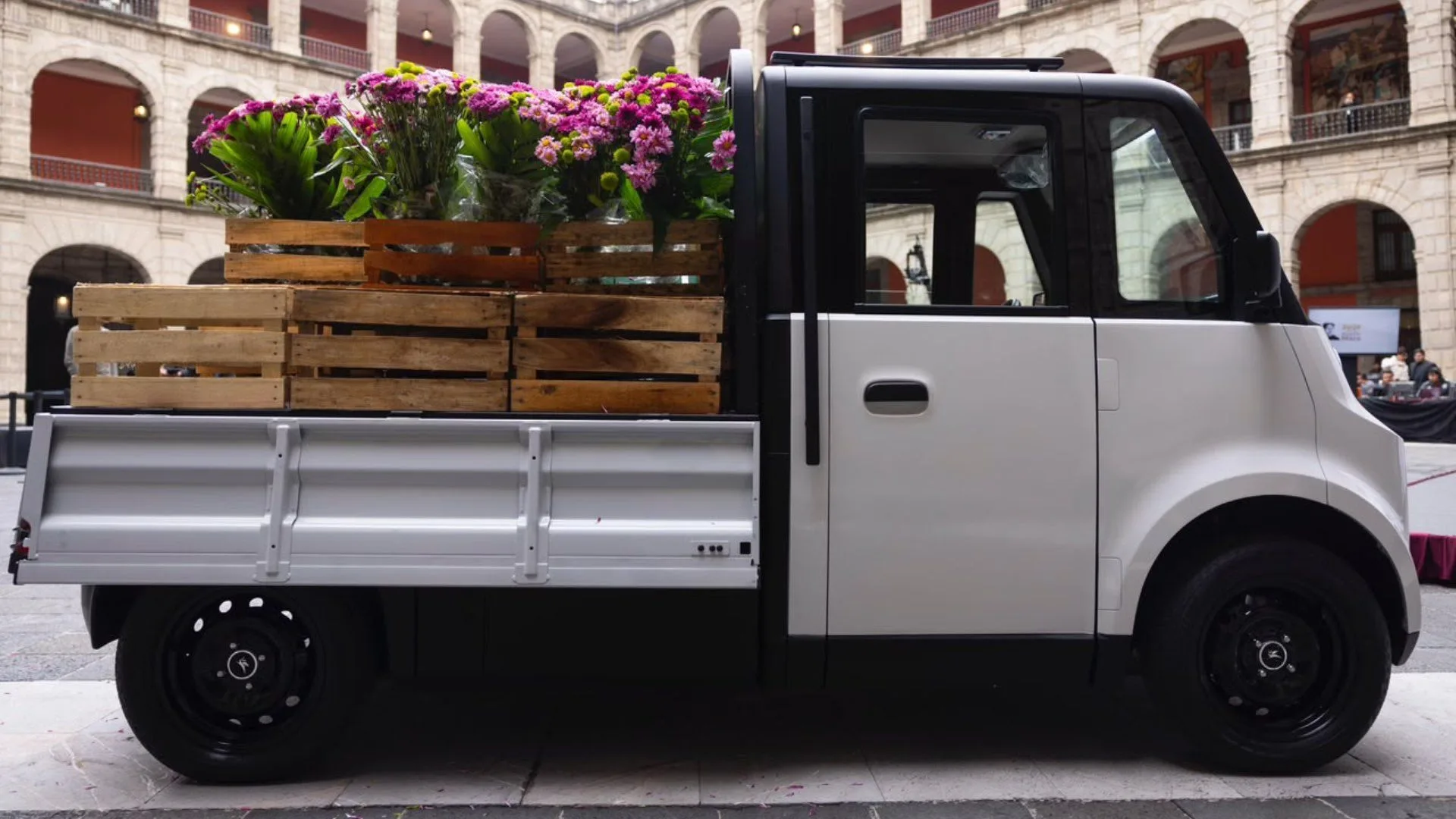 The Olinia cargo vehicle, an electric delivery vehicle with folding side panels, displayed at a presidential briefing in Mexico City.