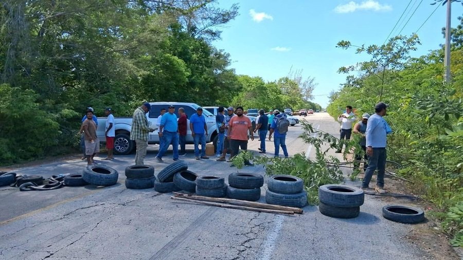 Protesters blocking a highway in Quintana Roo with a truck and debris, causing traffic to stop.