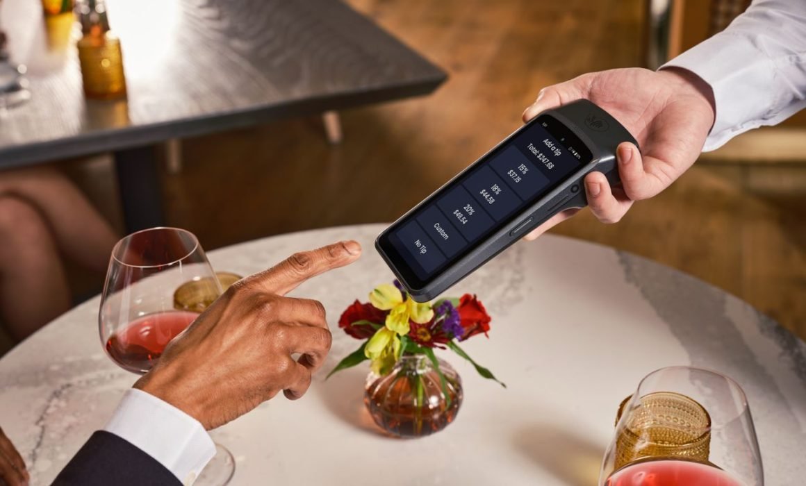 A customer pays at a restaurant using a card terminal while the receipt shows a mandatory tip charge