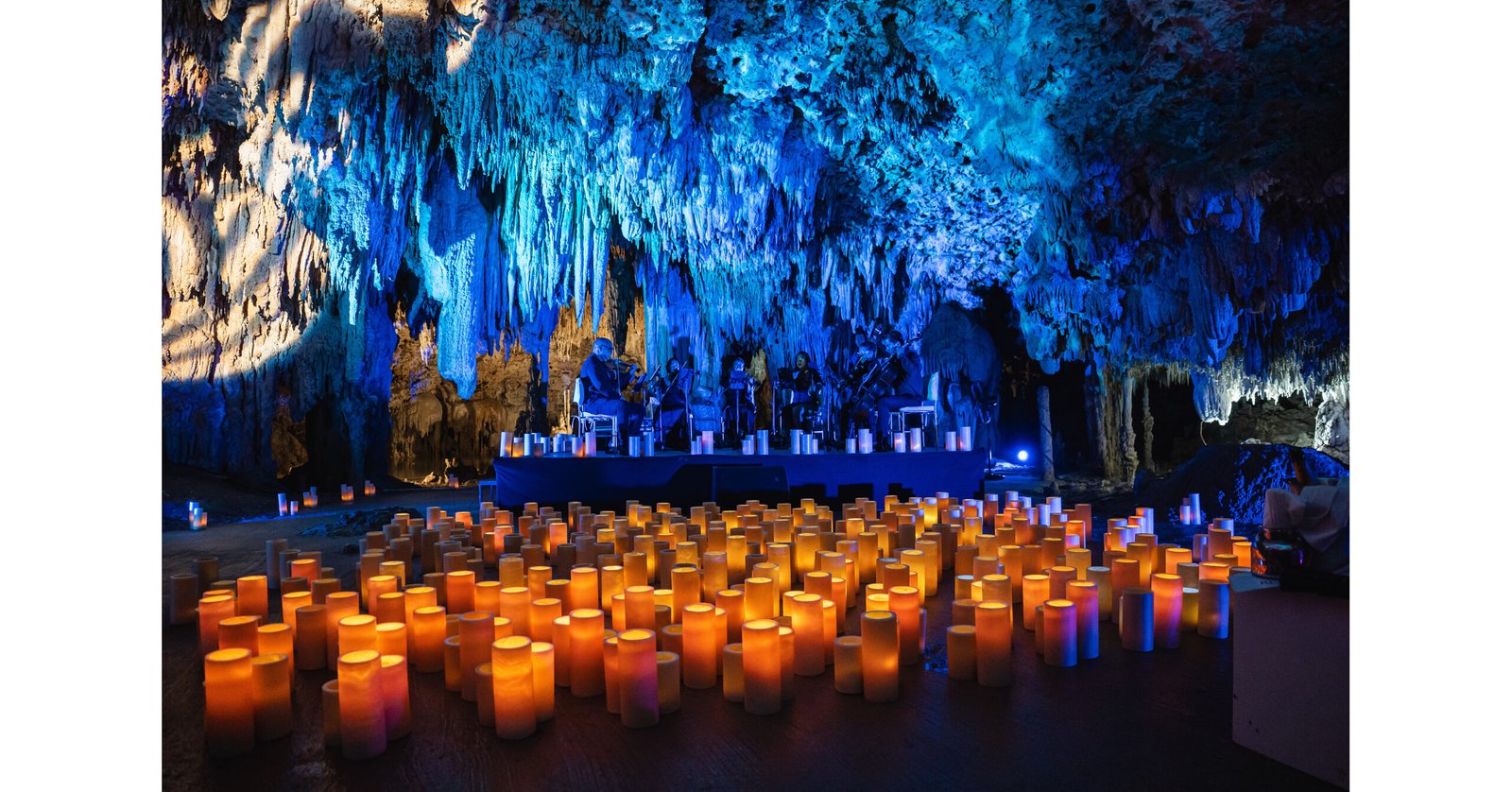 A symphony orchestra performing inside a limestone cenote surrounded by jungle in the Riviera Maya