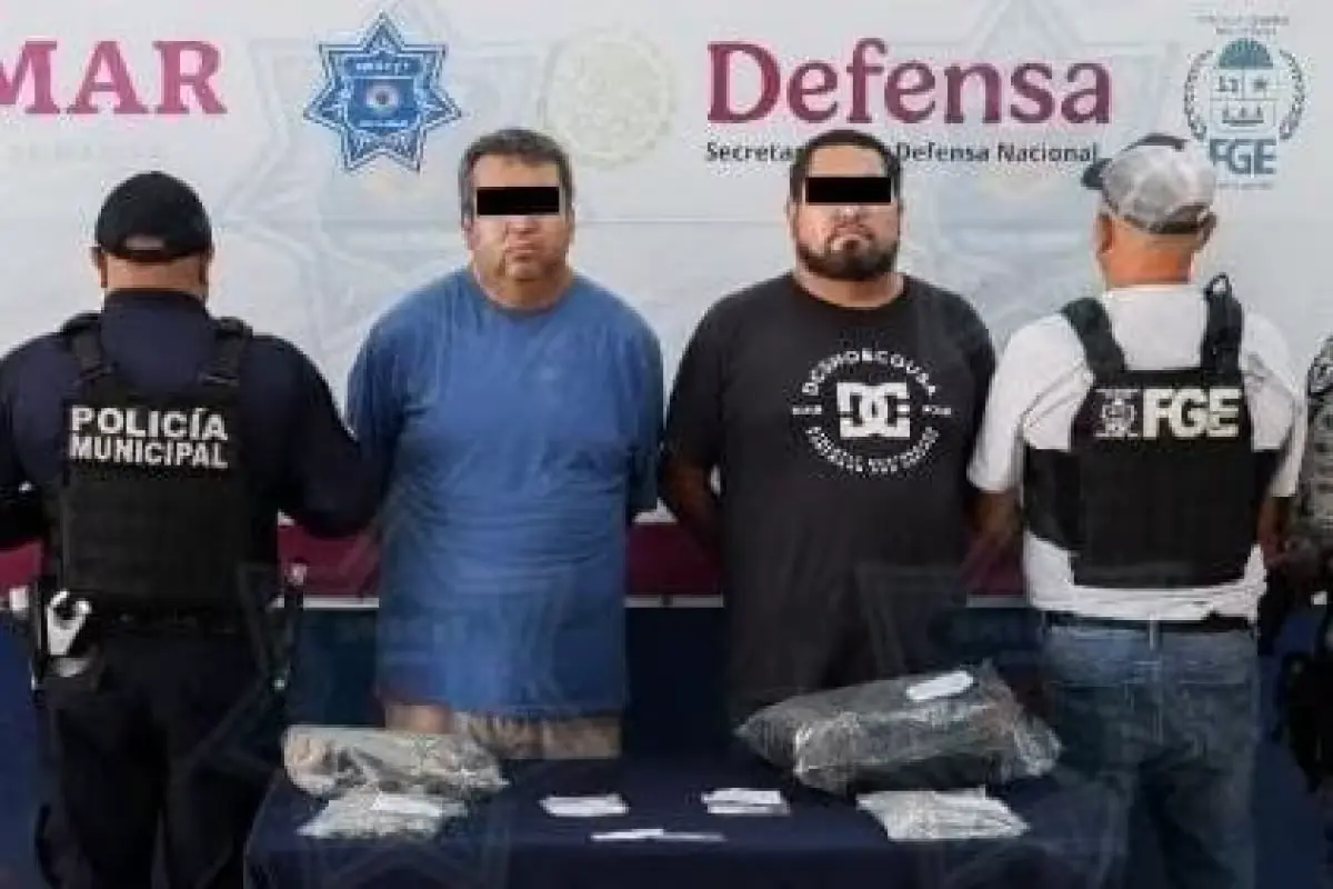 Police officers detain two men accused of scamming elderly people at ATMs in Cancun