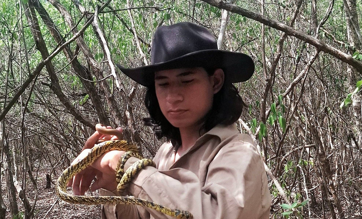 UADY biology student Diego Sánchez Herrera holds a rescued snake during his relocation project in Mérida.