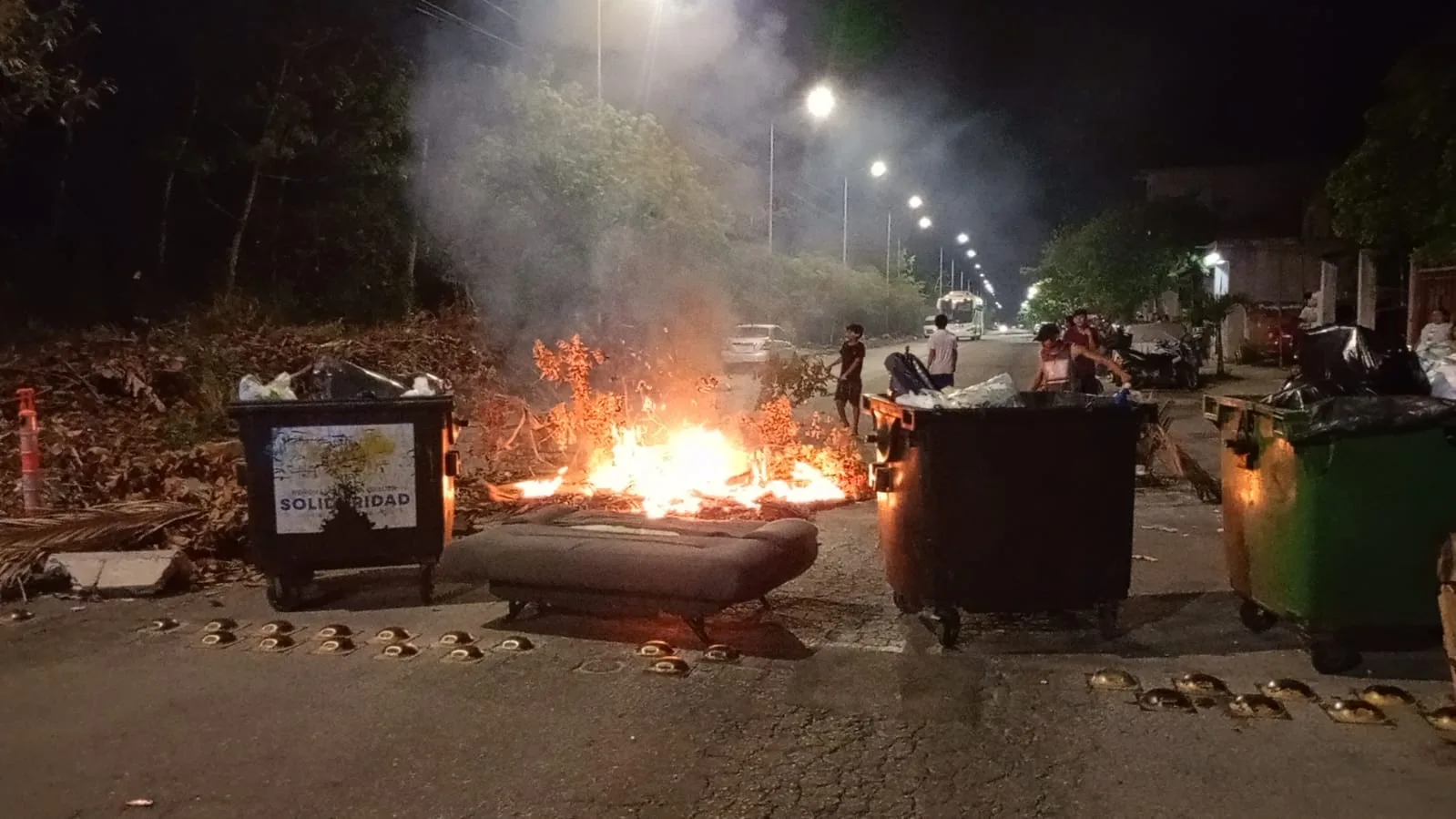 Residents block Avenida Loros in Villas del Sol with burning branches and tires during a protest over a three-day power outage.