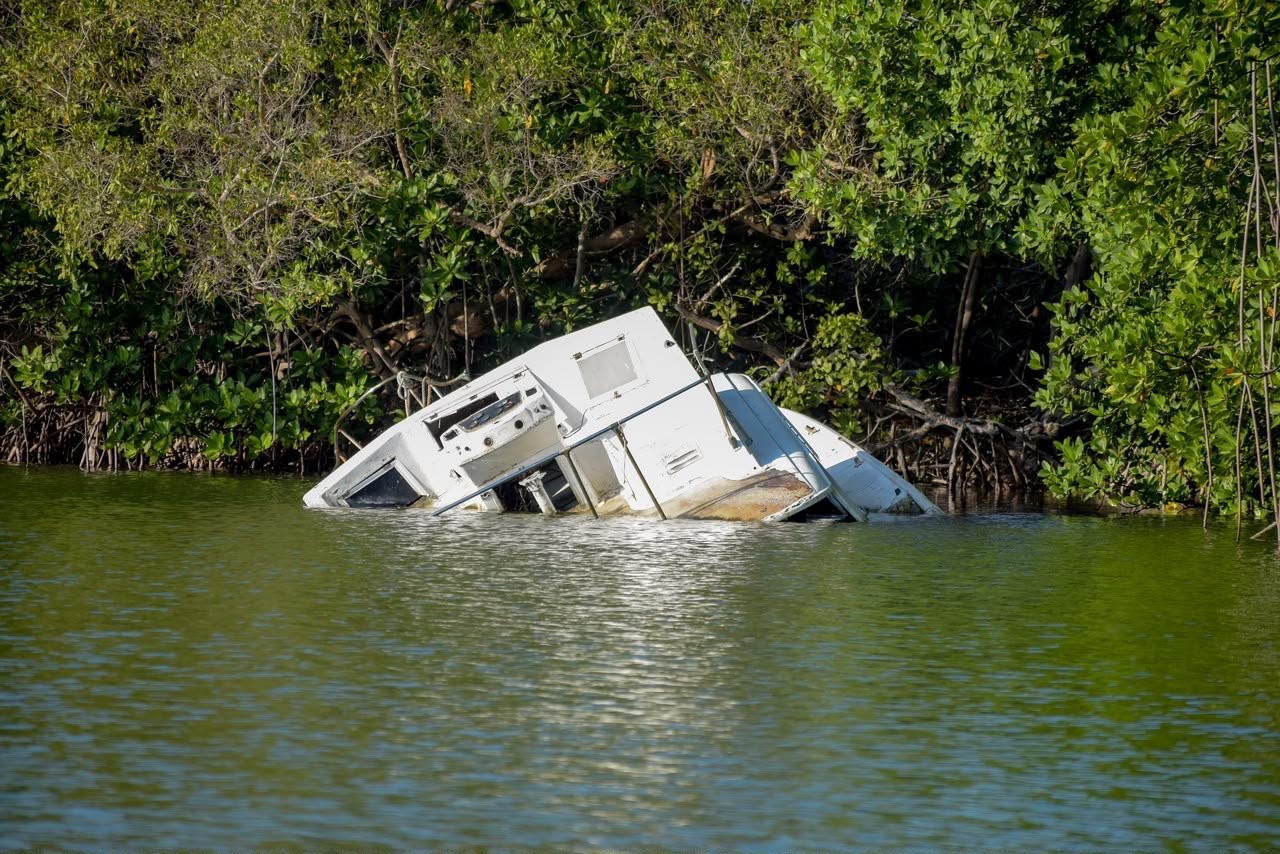 Derelict and partially sunken boats resting along the shore of the Nichupté Lagoon in Cancún, Quintana Roo