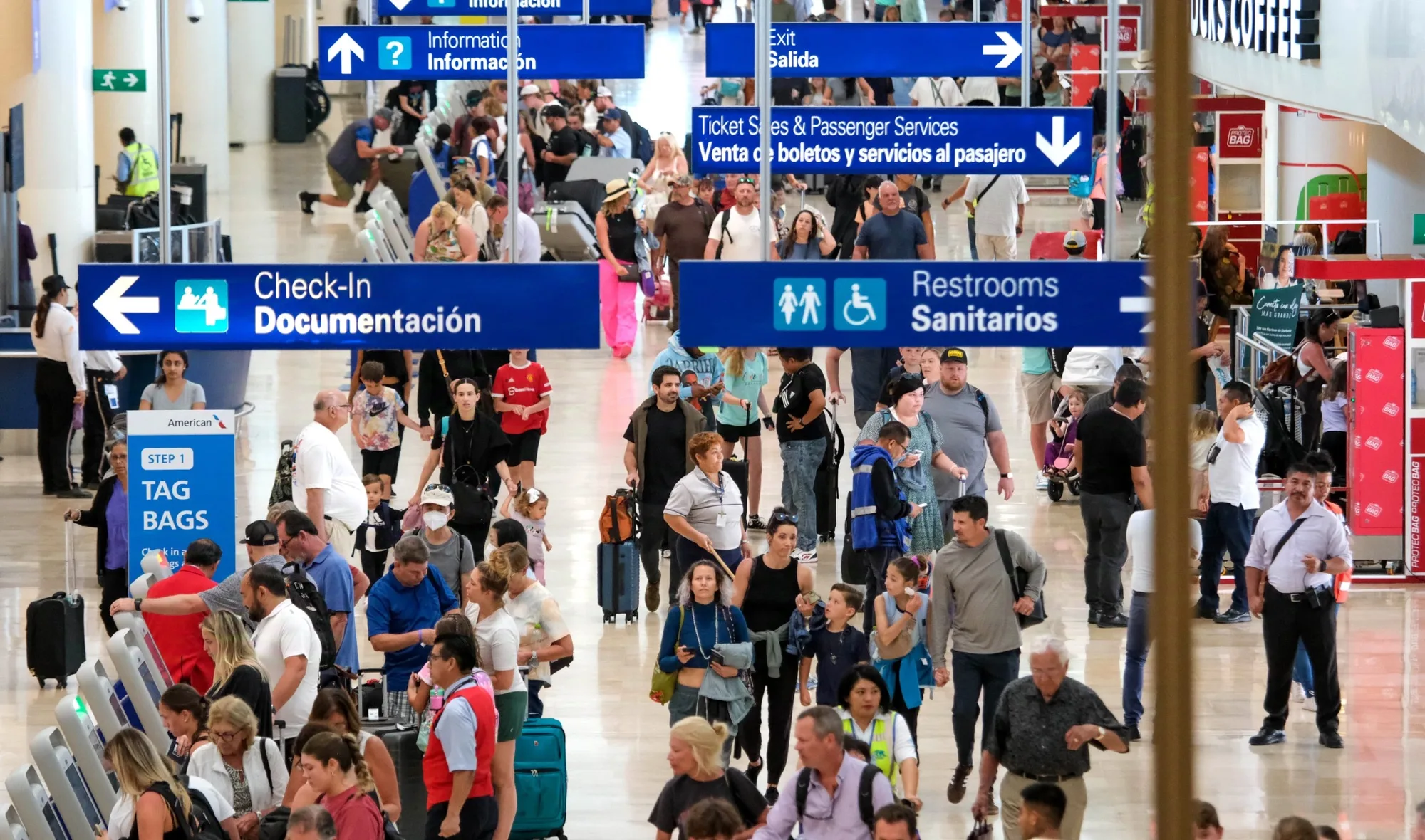 Travelers walking through the terminal at Cancún International Airport with luggage