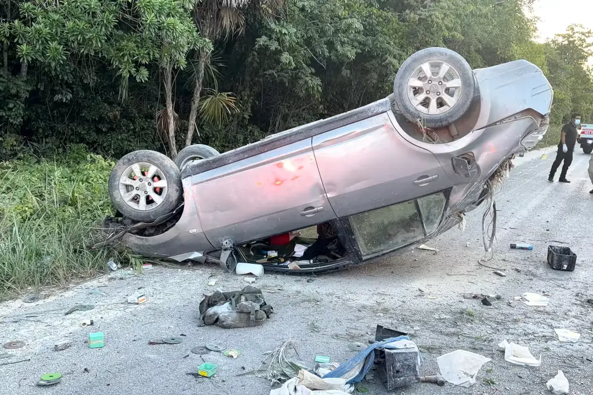 A gray Nissan Tiida overturned on the Tulum-Cobá highway with visible damage.