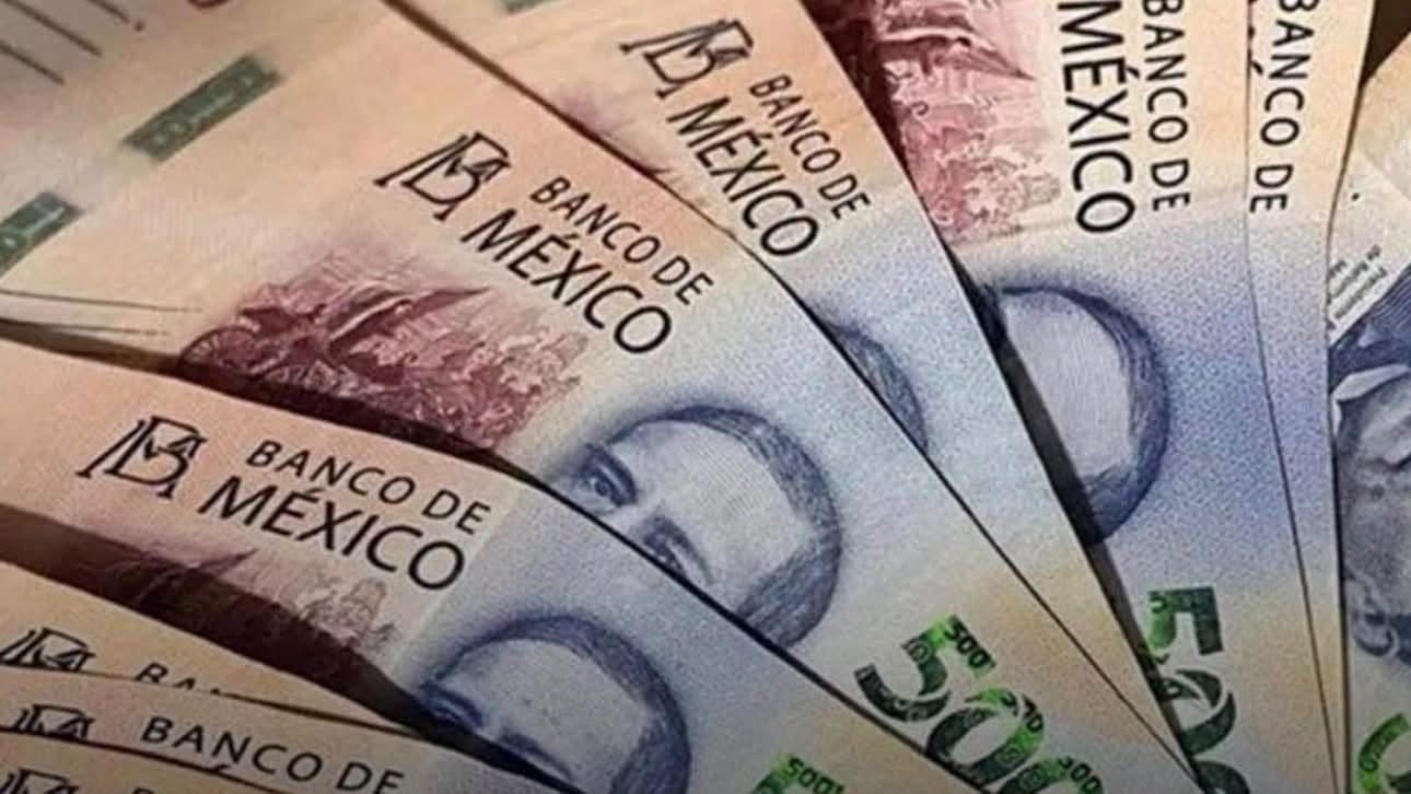 A hand holding Mexican 200-peso banknotes over a shop counter in Chetumal, Quintana Roo