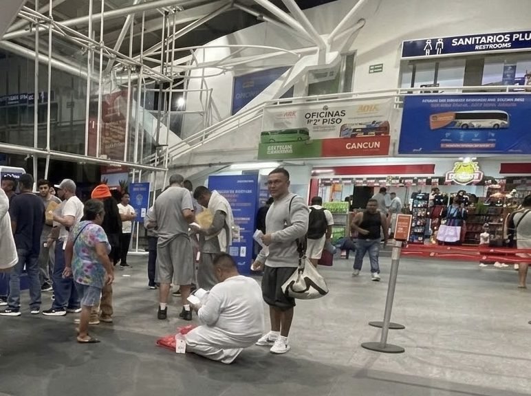 Travelers and migrants walking with luggage through an airport arrivals area in Quintana Roo, Mexico