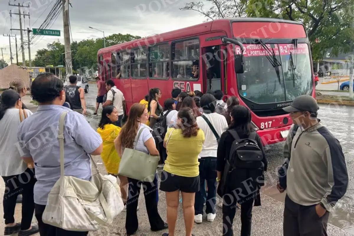 Flooded avenue in Cancún with stranded vehicles and commuters waiting for public transport in heavy rain