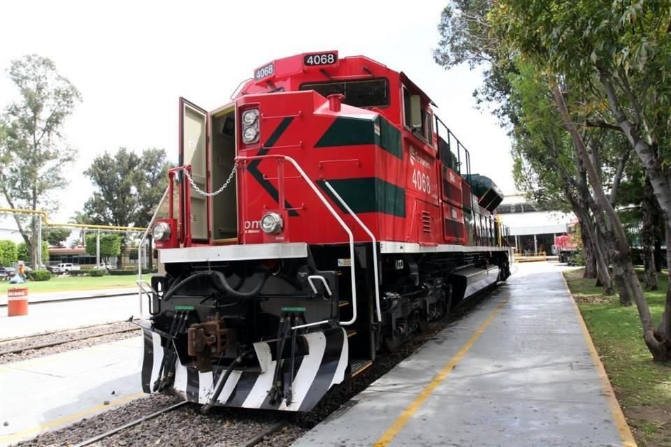 A long freight train hauling cargo containers travels along railway tracks in Mexico