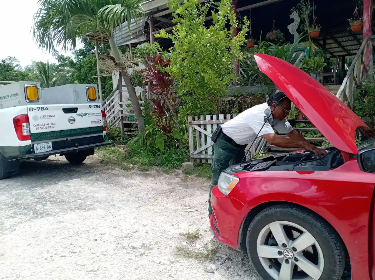 Green Angels roadside assistance vehicle helping tourists on a highway in Quintana Roo