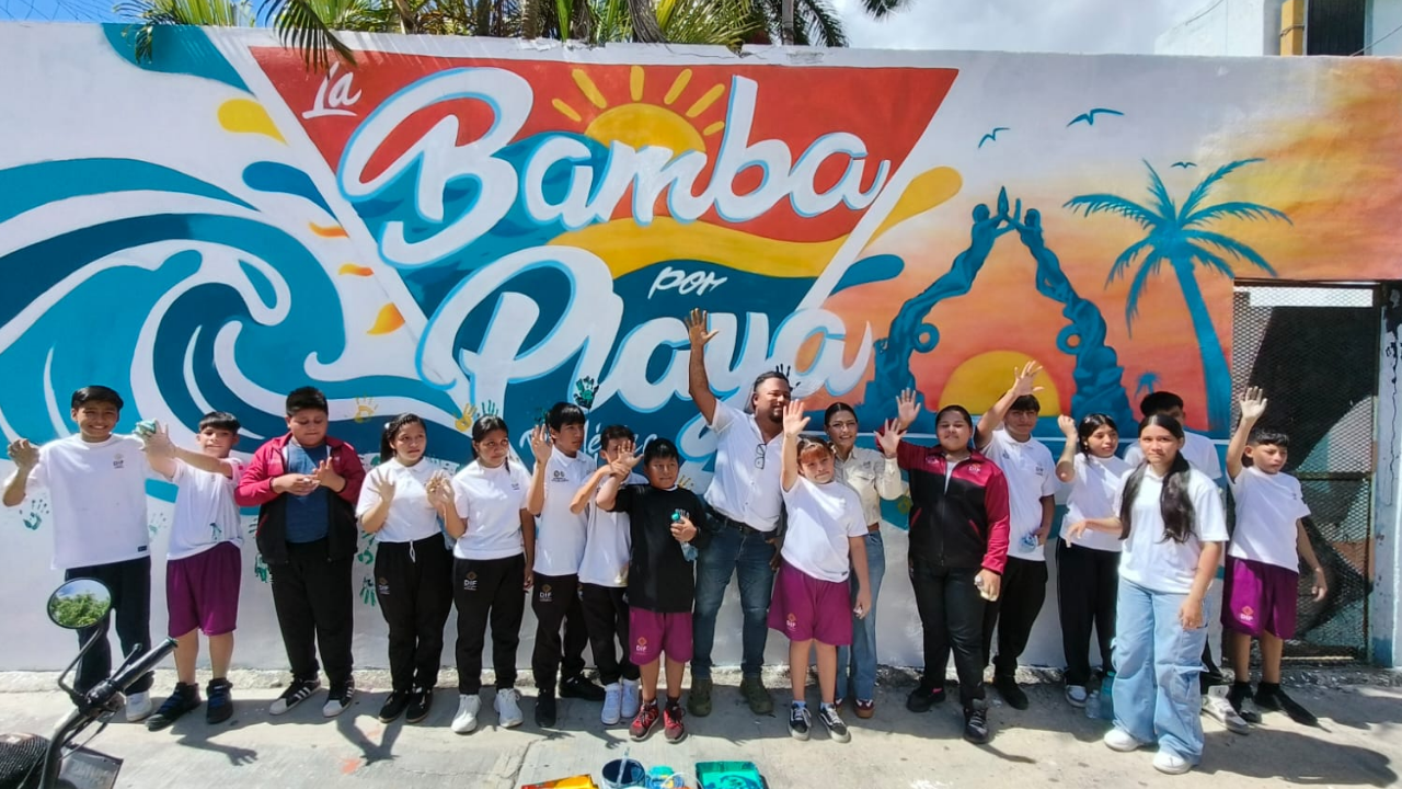 Children from the PAMAR program and older adults from the DIF Playa del Carmen day center stamp colored handprints on a community peace mural in downtown Playa del Carmen
