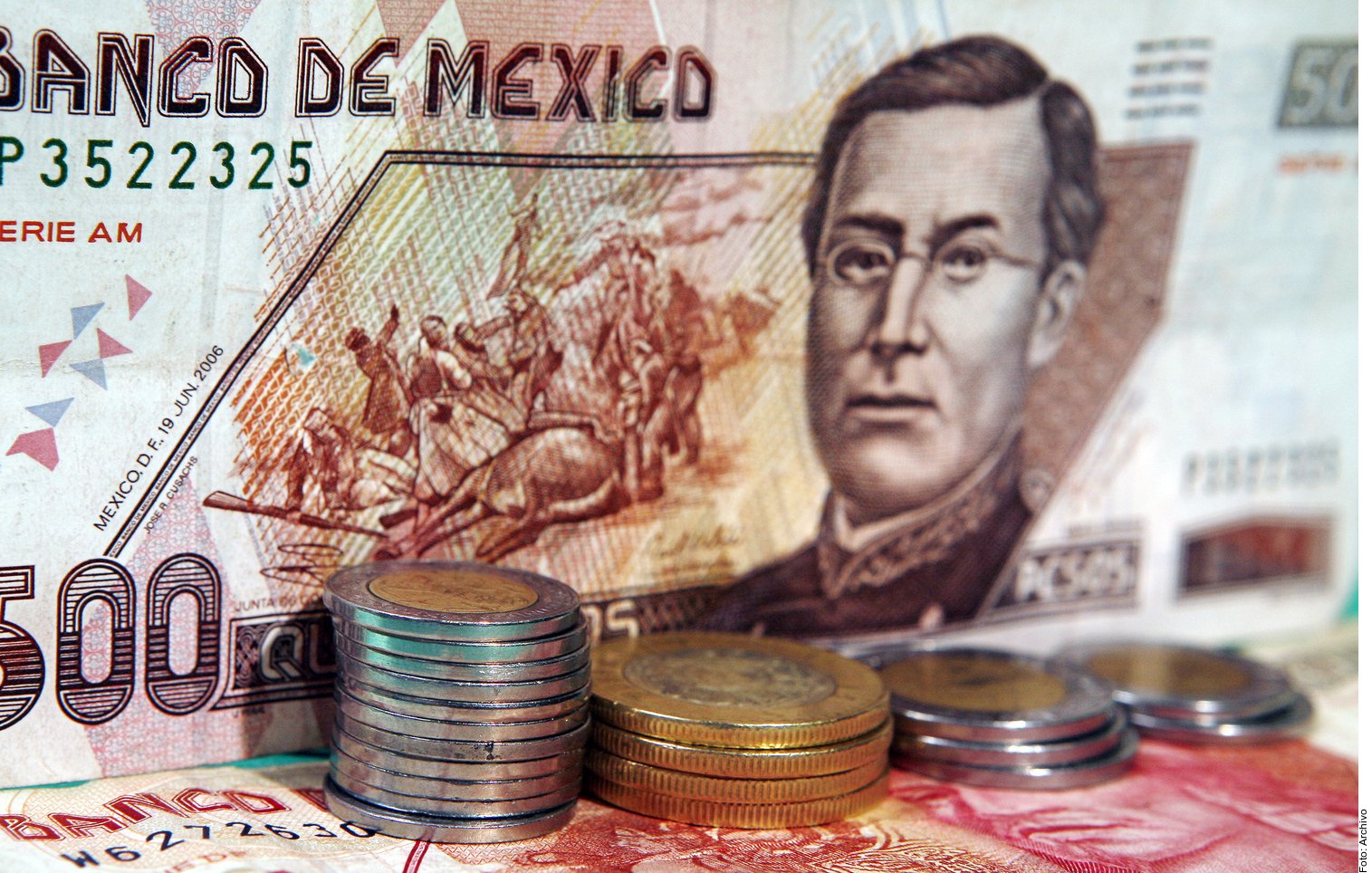 Mexican peso banknotes and coins spread on a surface, illustrating a proposal to restrict cash payments in Mexico