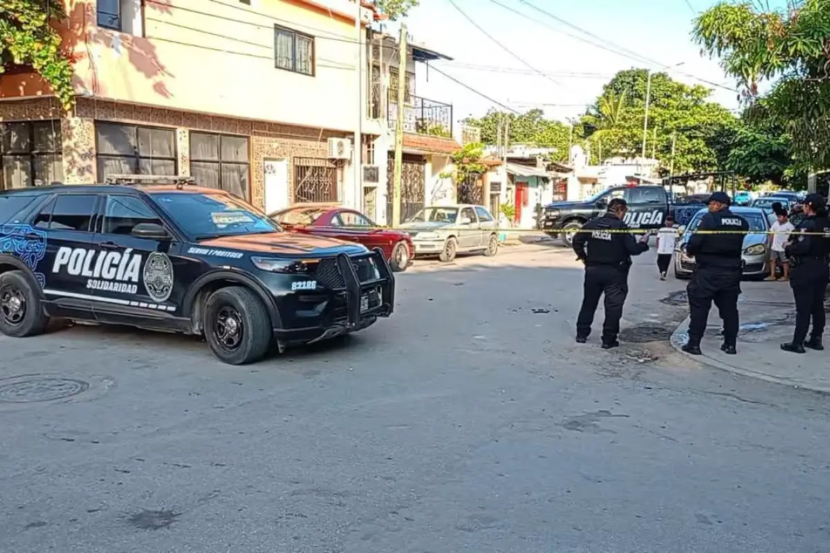 Police officers stand outside a home in southern Playa del Carmen after a shooting.