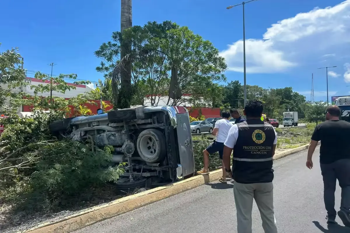 A gray pickup truck rests on its roof on the central median of Federal Highway 307 between Cancún and Puerto Morelos after a rollover.