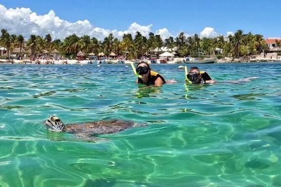 Tour boats and snorkelers in the shallow turquoise water of Akumal bay on Mexico's Riviera Maya