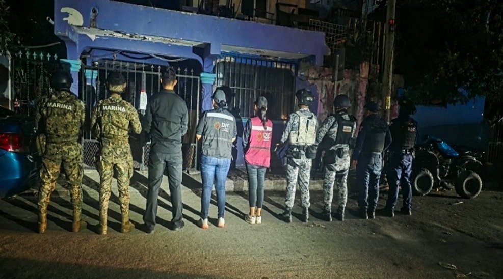 Police vehicles and officers outside a property in Playa del Carmen during a search tied to a labor exploitation investigation